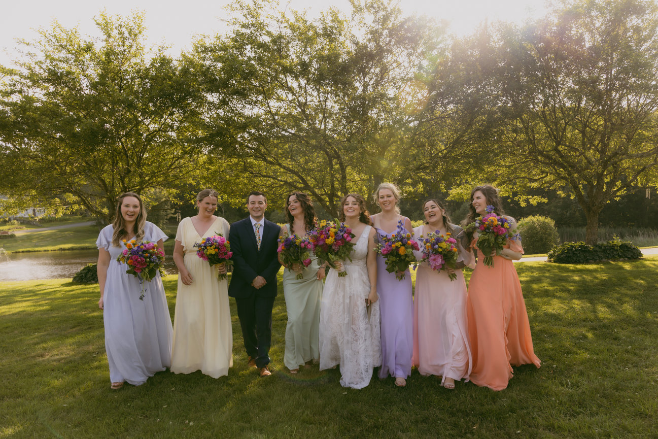 Bride and bridesmaids in a sunlit outdoor setting at a Connecticut wedding venue.